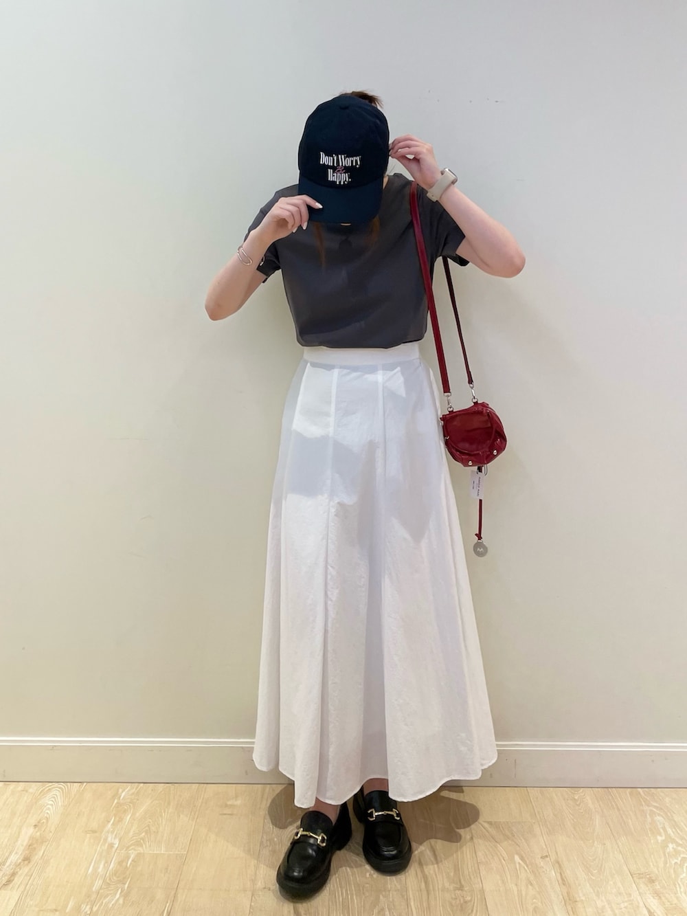 レッド系のショルダーバッグ、ホワイト系のスカート、グレー系のTシャツ/カットソーを着用したレディースの春コーディネートの2枚目の写真