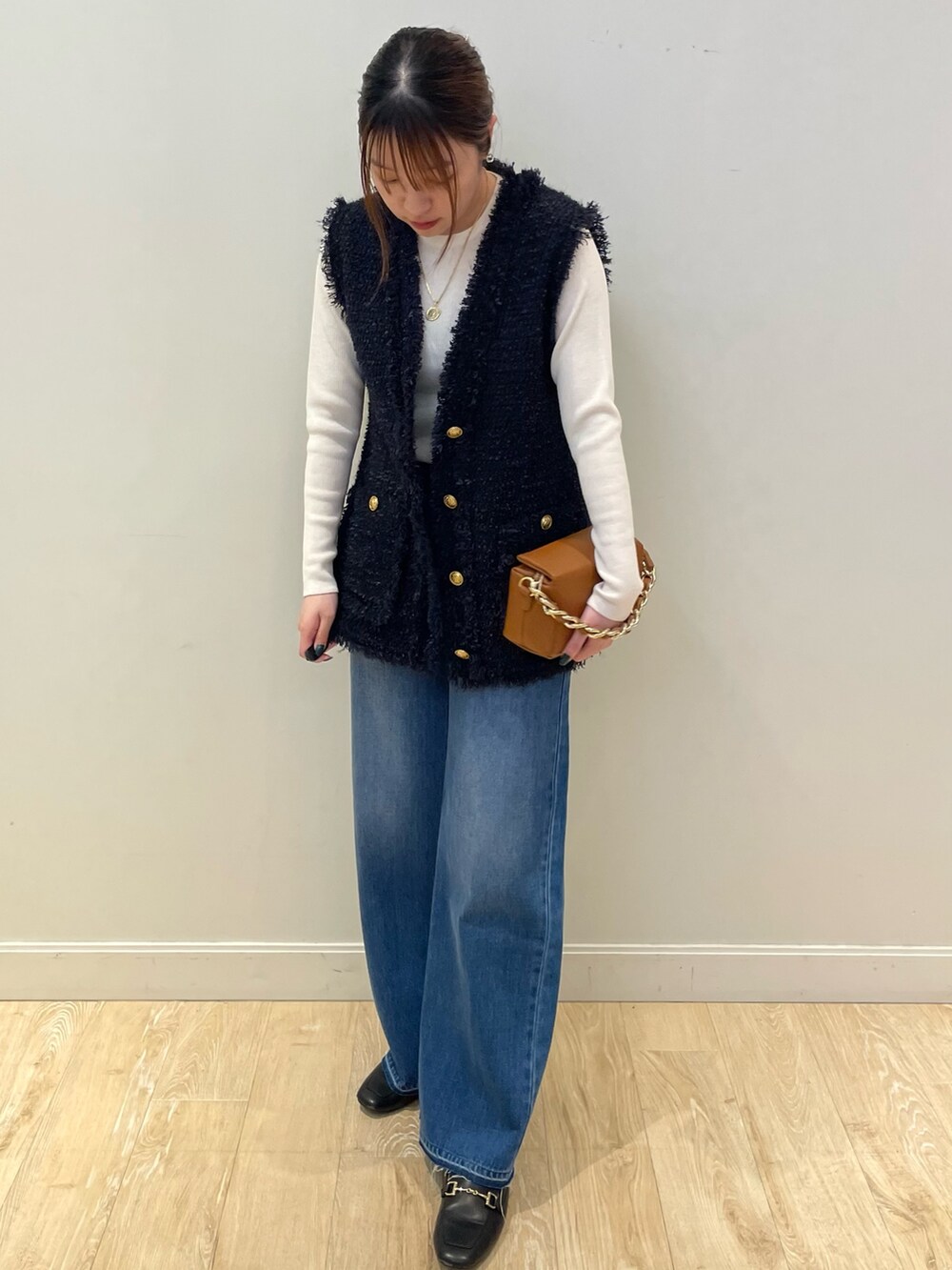 ブルー系のデニムパンツ、ホワイト系のニット/セーター、ブルー系のベストを着用したレディースの秋コーディネートの2枚目の写真