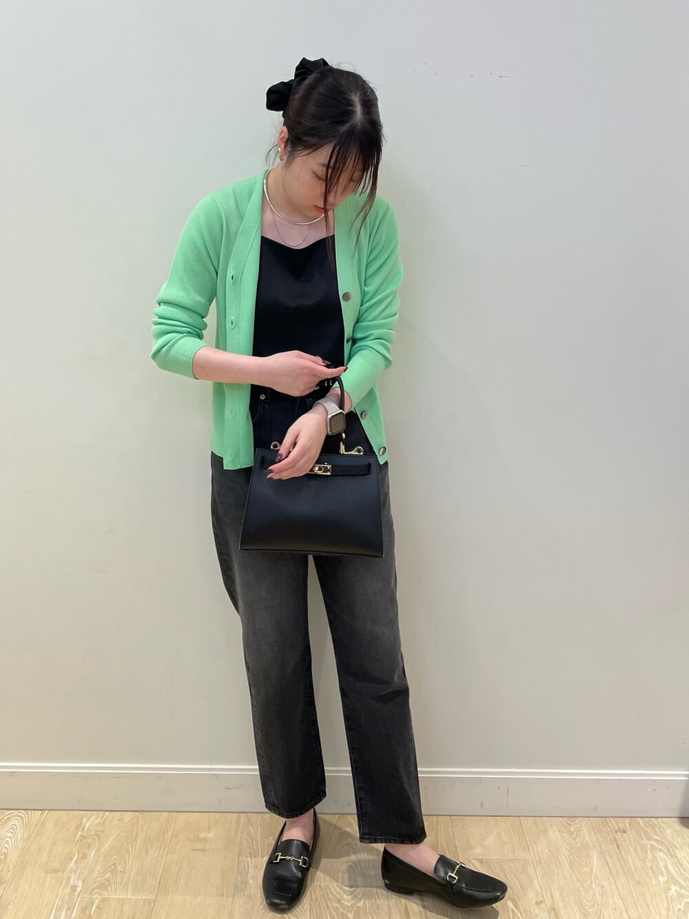 グリーン系のカーディガン/ボレロ、ブラック系のタンクトップ、ブラック系のデニムパンツを着用したレディースの冬コーディネートの3枚目の写真