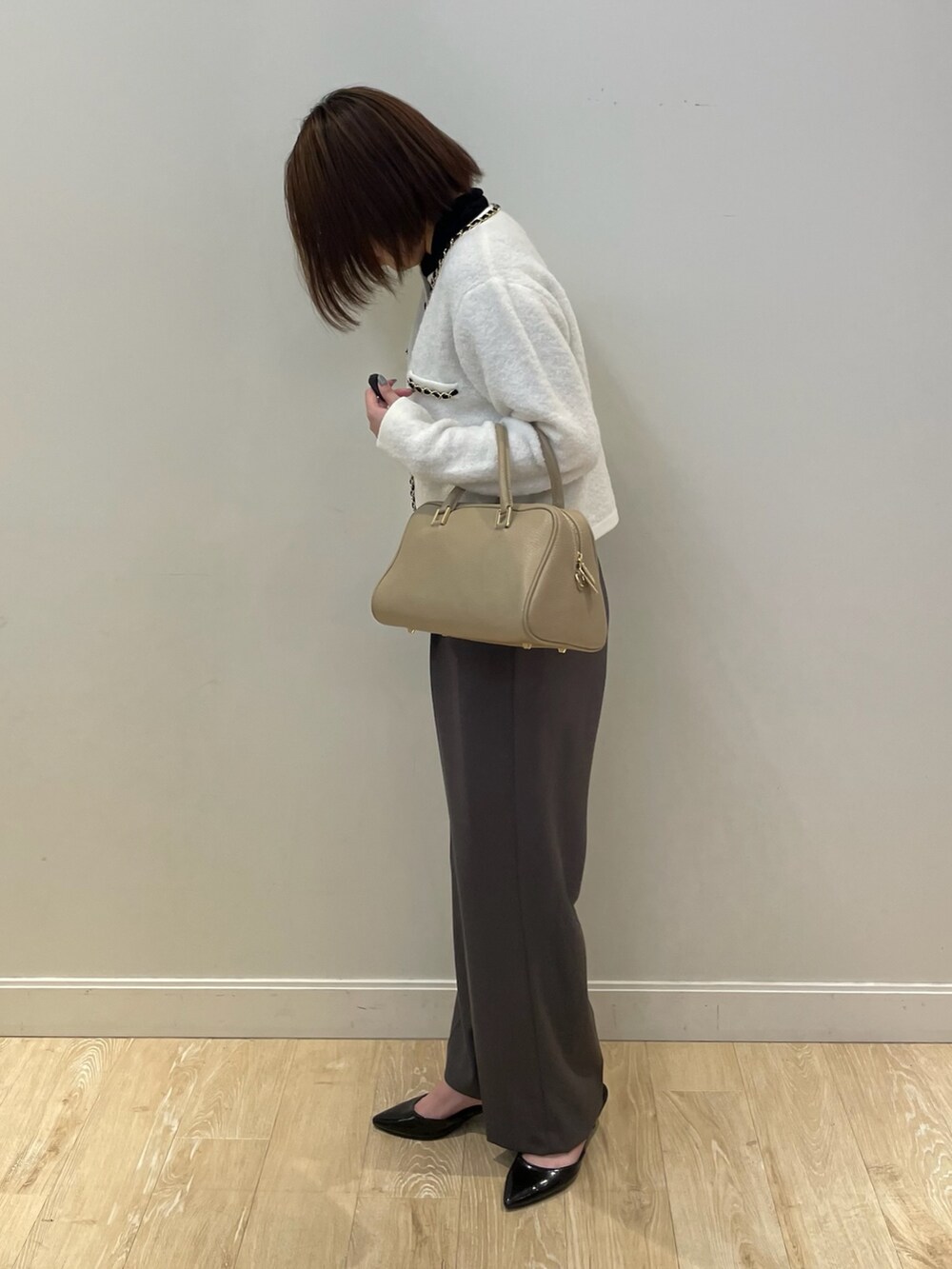 ブラック系のニット/セーター、ホワイト系のカーディガン/ボレロ、ベージュ系のショルダーバッグを着用したレディースの秋コーディネートの2枚目の写真