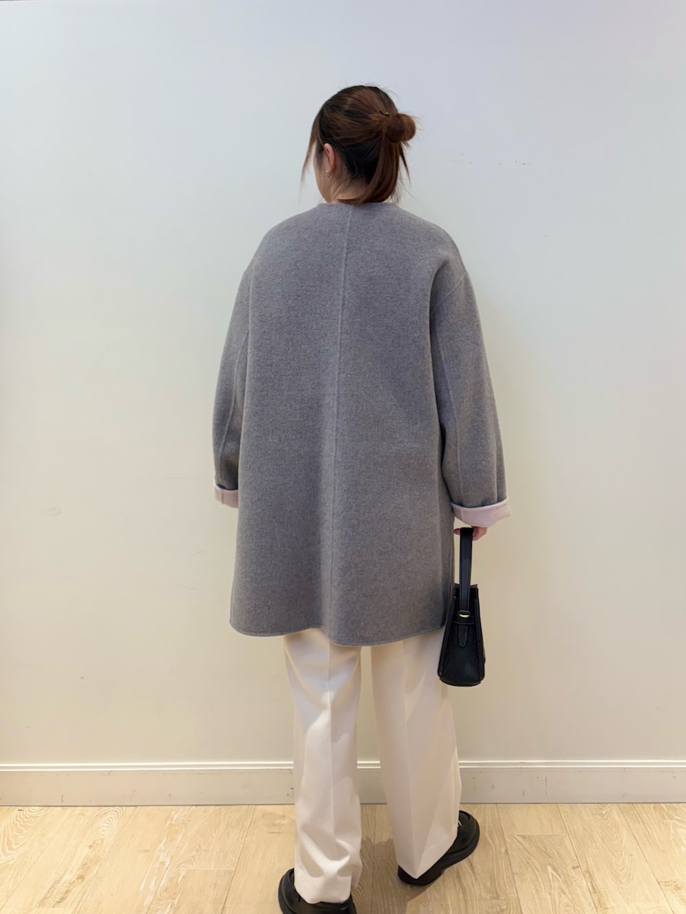 ベージュ系のニット/セーター、ホワイト系のその他パンツ、ブラック系のショルダーバッグを着用したレディースの冬コーディネートの2枚目の写真