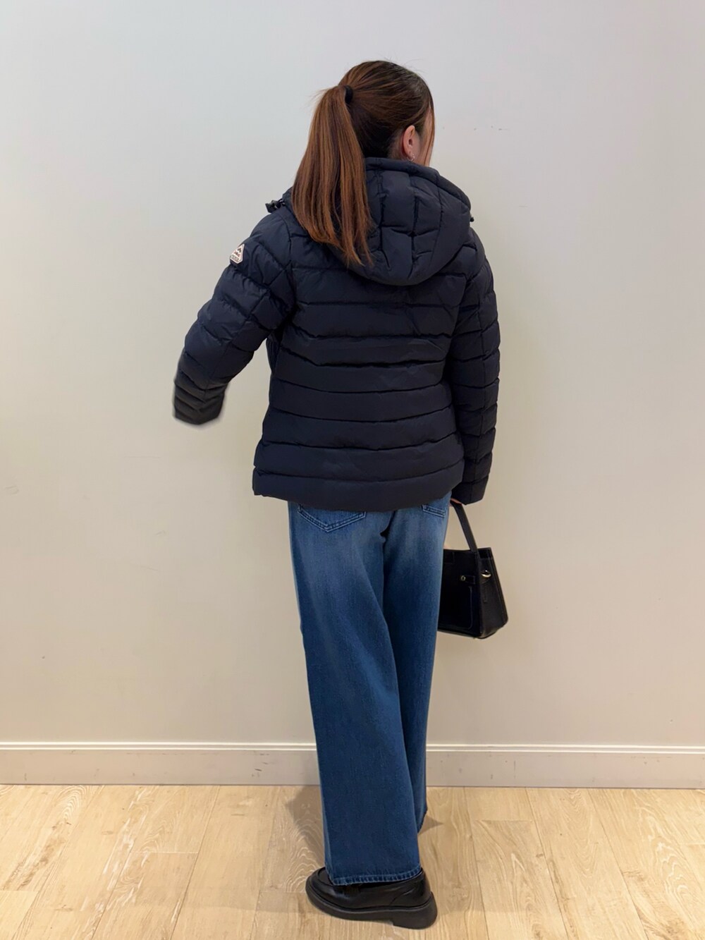 イエロー系のニット/セーター、ブルー系のデニムパンツ、ブラック系のショルダーバッグを着用したレディースの秋コーディネートの2枚目の写真