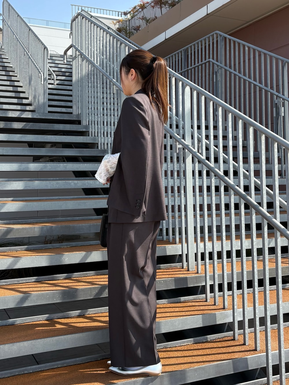 ブラック系のショルダーバッグ、ブラック系のTシャツ/カットソー、グレー系のテーラードジャケットを着用したレディースの冬コーディネートの2枚目の写真