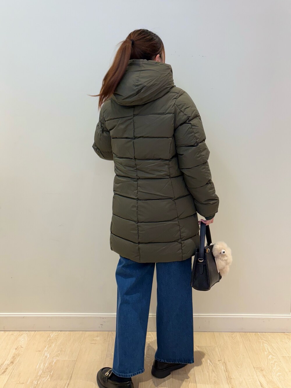 イエロー系のニット/セーター、ブルー系のデニムパンツ、ブラック系のショルダーバッグを着用したレディースの秋コーディネートの3枚目の写真