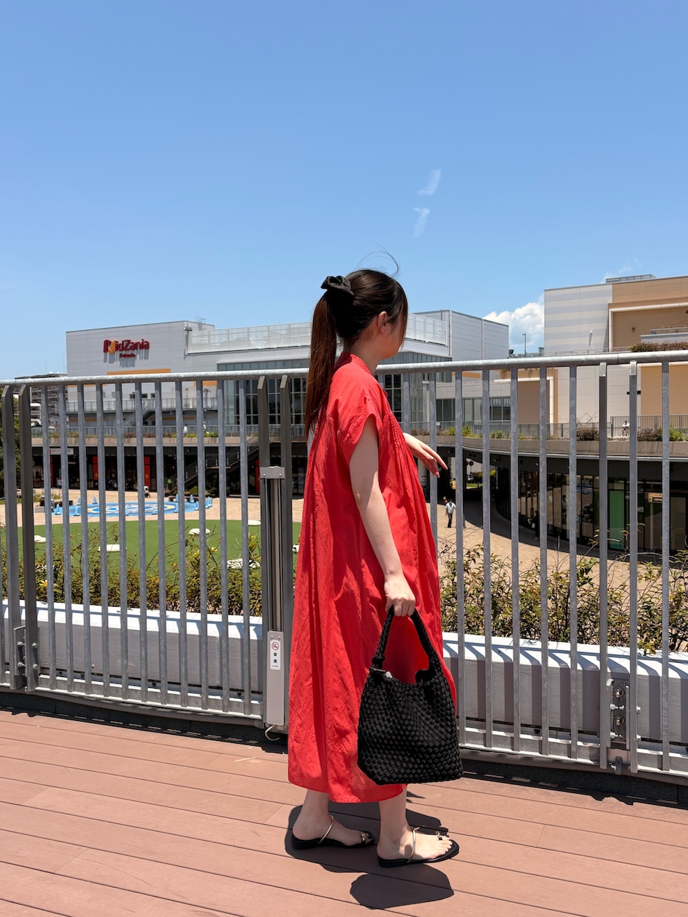 ブラック系のショルダーバッグ、レッド系のワンピースを着用したレディースの夏コーディネートの2枚目の写真