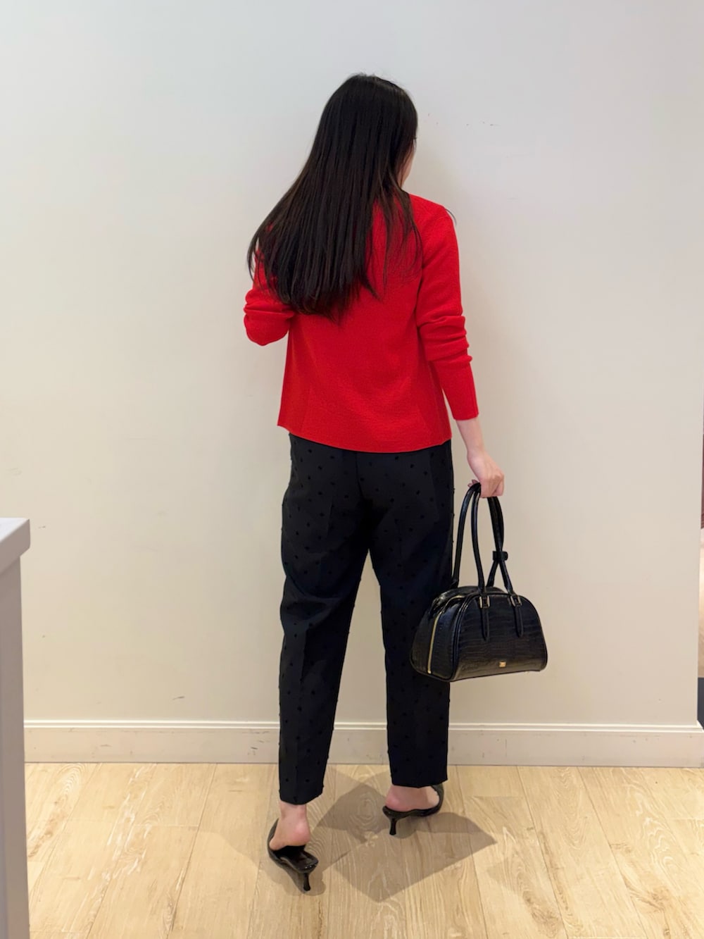 ブラック系のボストンバッグ、ブラック系のその他パンツ、レッド系のカーディガン/ボレロを着用したレディースの秋コーディネートの5枚目の写真