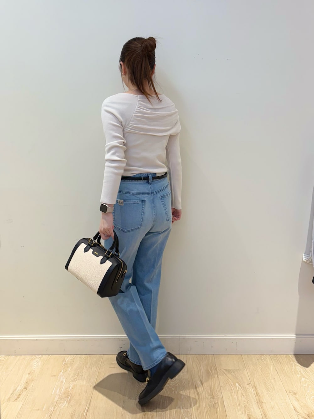 ブラック系のボストンバッグ、ブルー系のデニムパンツ、ベージュ系のニット/セーターを着用したレディースの春コーディネートの2枚目の写真