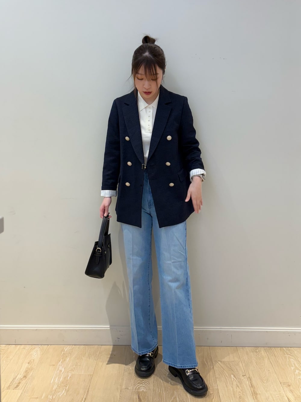 ブルー系のデニムパンツ、ブラック系のショルダーバッグ、ホワイト系のニット/セーターを着用したレディースの冬コーディネートの4枚目の写真