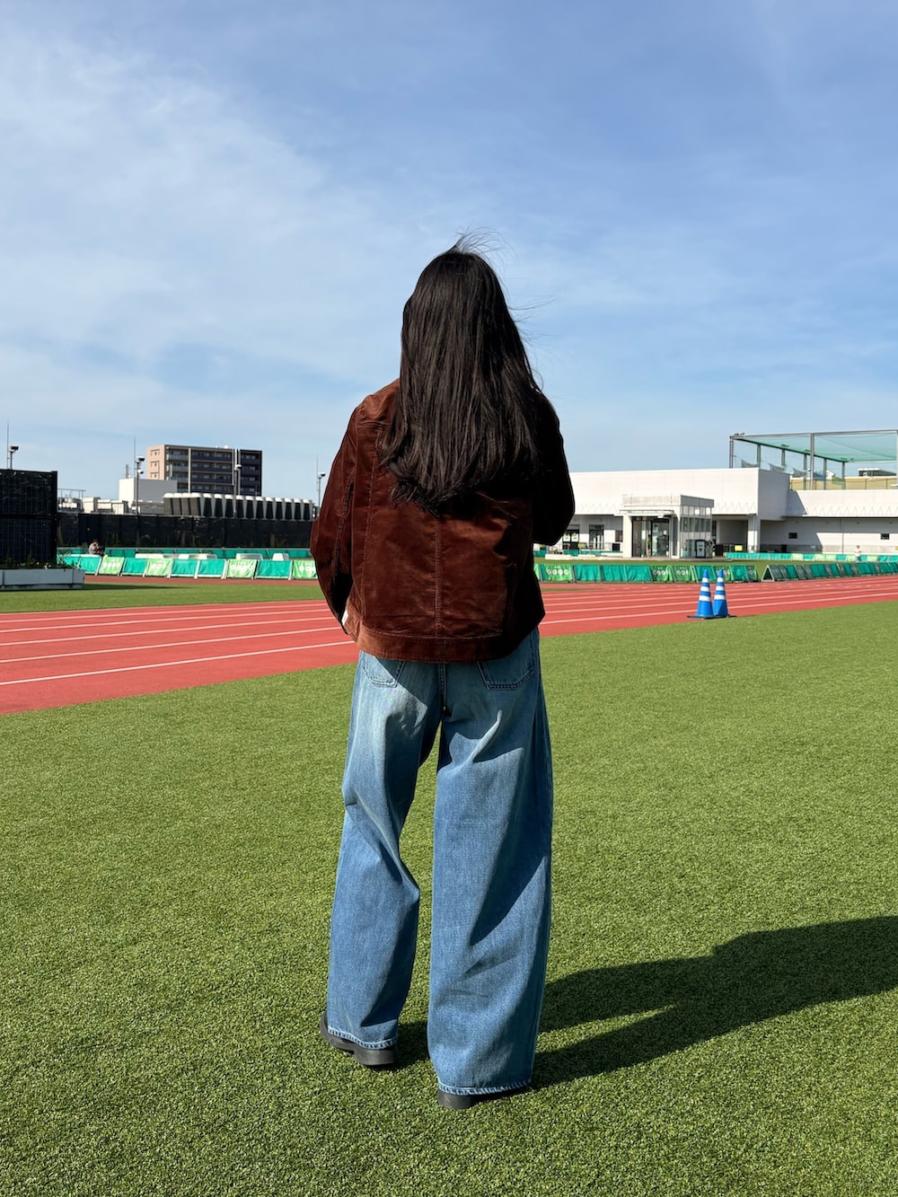 ブルー系のデニムパンツ、ホワイト系のTシャツ/カットソー、ブラウン系のブルゾンを着用したレディースの夏コーディネートの2枚目の写真