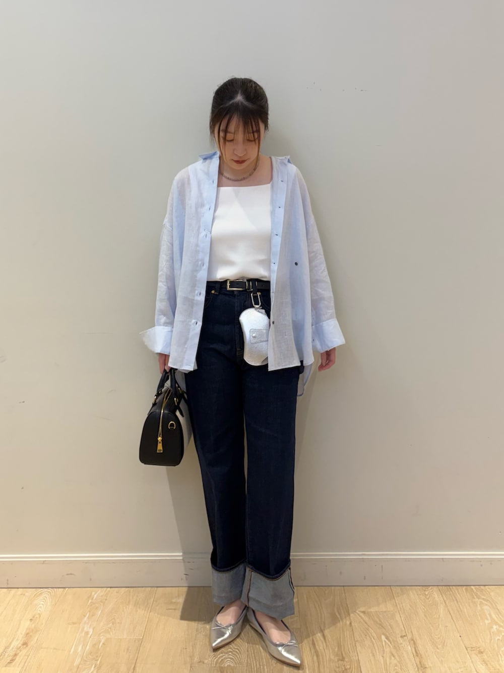 ブラック系のボストンバッグ、ブルー系のデニムパンツ、ホワイト系のタンクトップを着用したレディースの春コーディネートの3枚目の写真