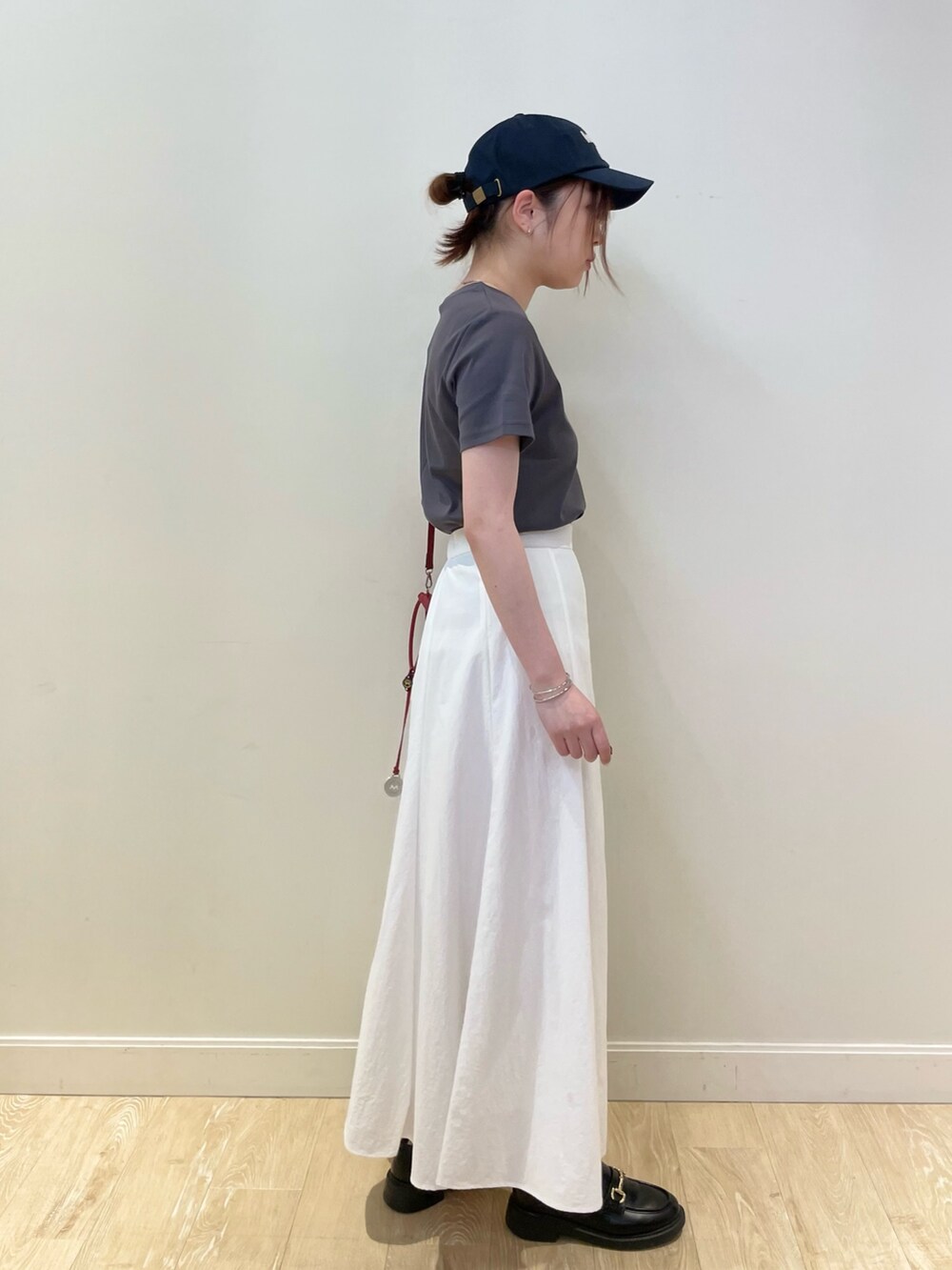 レッド系のショルダーバッグ、ホワイト系のスカート、グレー系のTシャツ/カットソーを着用したレディースの春コーディネートの5枚目の写真