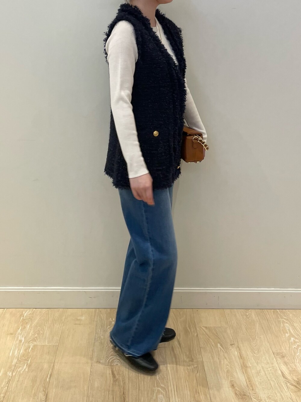 ブルー系のデニムパンツ、ホワイト系のニット/セーター、ブルー系のベストを着用したレディースの秋コーディネートの3枚目の写真