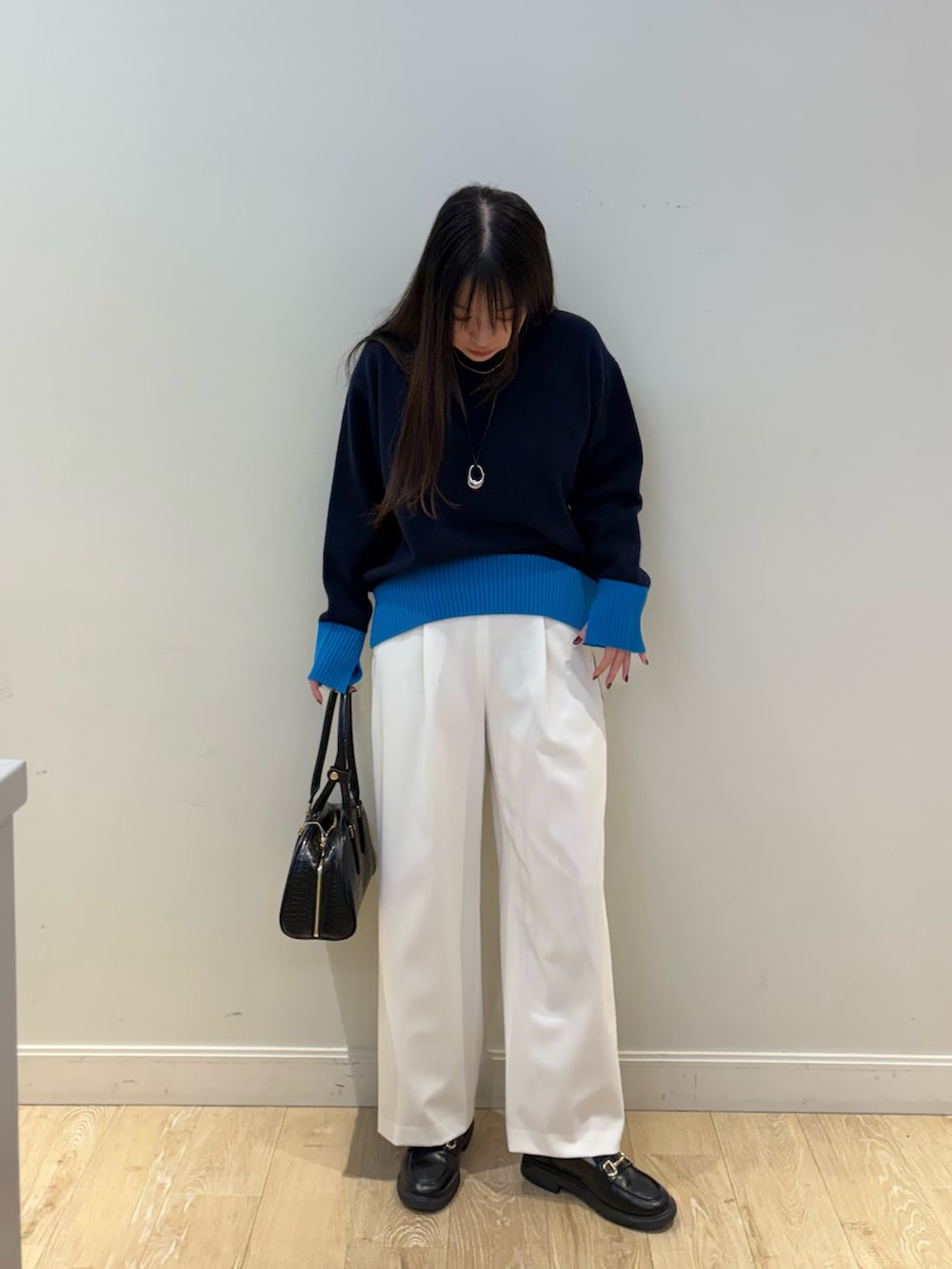 ブラック系のボストンバッグ、ホワイト系のその他パンツ、ブルー系のニット/セーターを着用したレディースの秋コーディネートの4枚目の写真