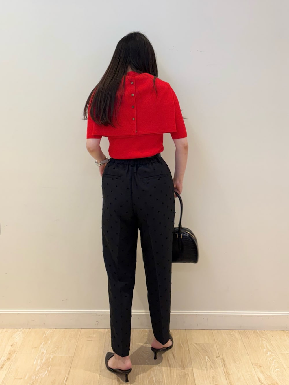 ブラック系のボストンバッグ、ブラック系のその他パンツ、レッド系のカーディガン/ボレロを着用したレディースの秋コーディネートの2枚目の写真