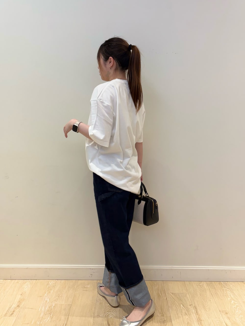 ブルー系のデニムパンツ、ブラック系のボストンバッグ、ホワイト系のTシャツ/カットソーを着用したレディースの春コーディネートの3枚目の写真