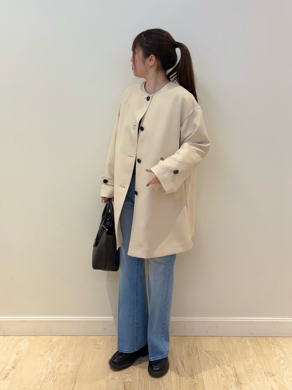 ブラック系のトートバッグ、ブルー系のデニムパンツ、ブラック系のニット/セーターを着用したレディースの冬コーディネートの6枚目の写真