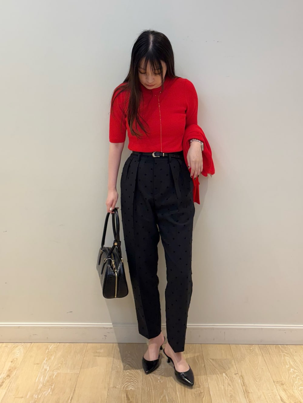 ブラック系のボストンバッグ、ブラック系のその他パンツ、レッド系のカーディガン/ボレロを着用したレディースの秋コーディネートの6枚目の写真
