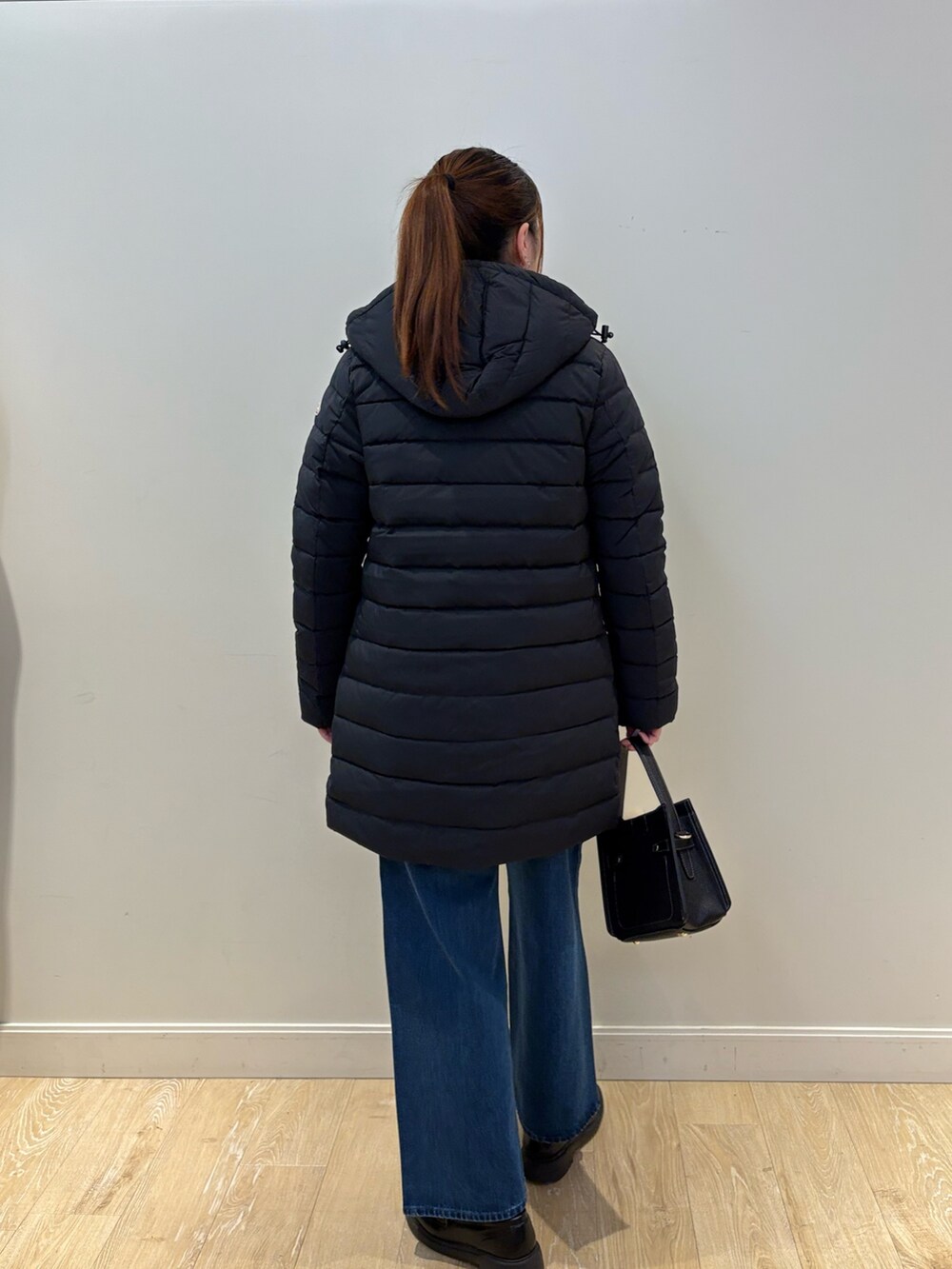 イエロー系のニット/セーター、ブラック系のショルダーバッグ、ブルー系のデニムパンツを着用したレディースの秋コーディネートの2枚目の写真