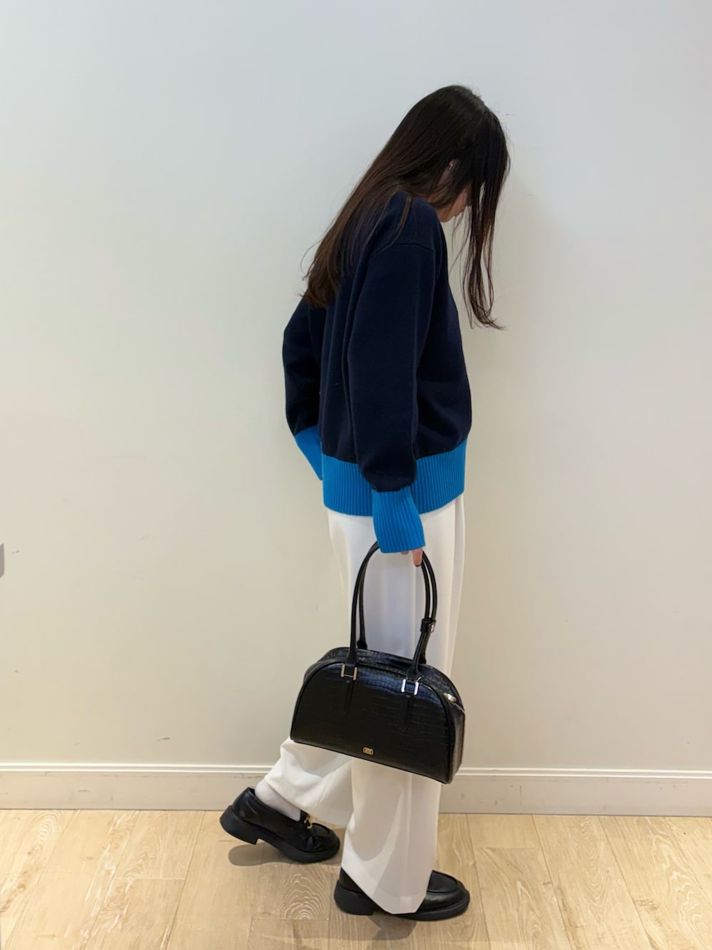ブラック系のボストンバッグ、ホワイト系のその他パンツ、ブルー系のニット/セーターを着用したレディースの秋コーディネートの3枚目の写真