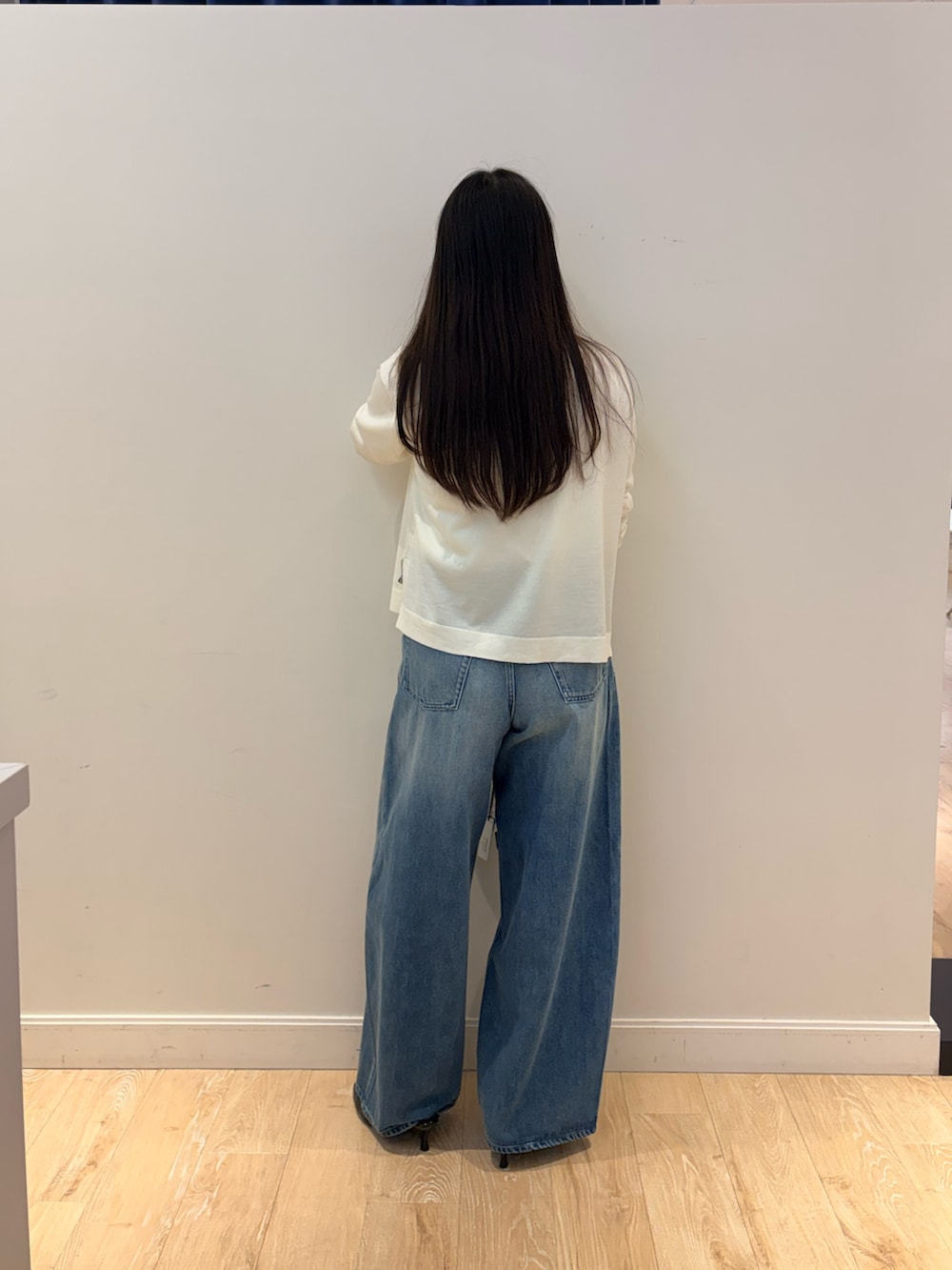 ブラック系のショルダーバッグ、ブルー系のデニムパンツ、ホワイト系のニット/セーターを着用したレディースの秋コーディネートの4枚目の写真