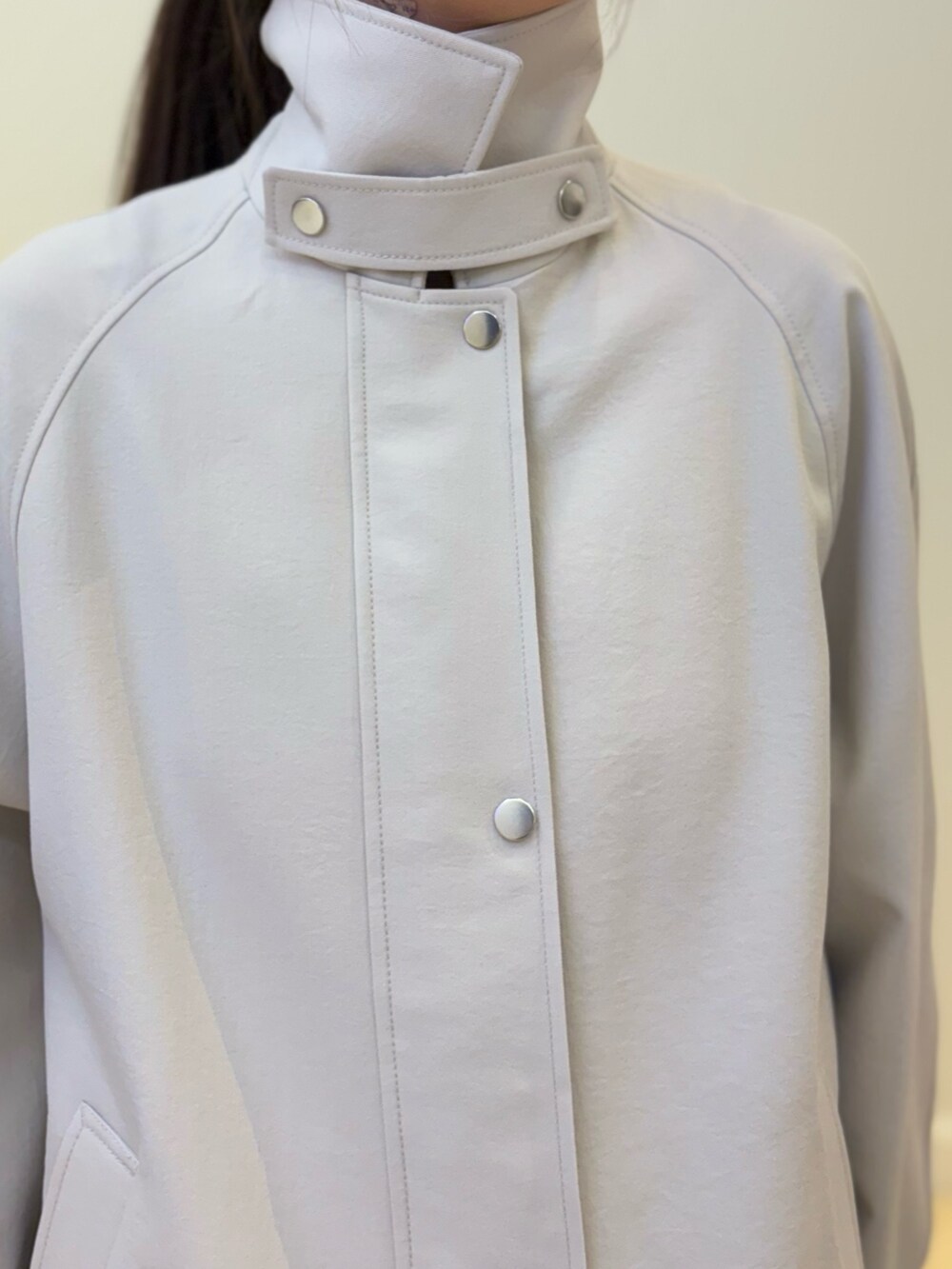 ブルー系のデニムパンツ、ブラック系のトートバッグ、ベージュ系のステンカラーコートを着用したレディースの冬コーディネートの5枚目の写真