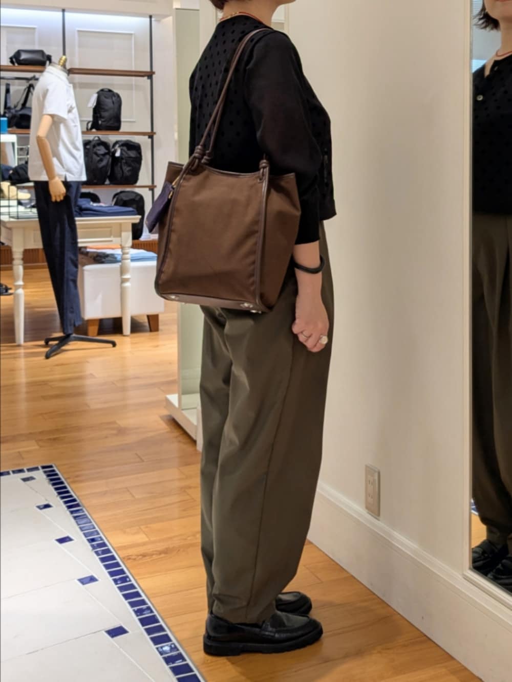 ブラック系のカーディガン/ボレロ、グリーン系のチノパンツ、ブラック系のドレスシューズを着用したレディースの夏コーディネートの3枚目の写真