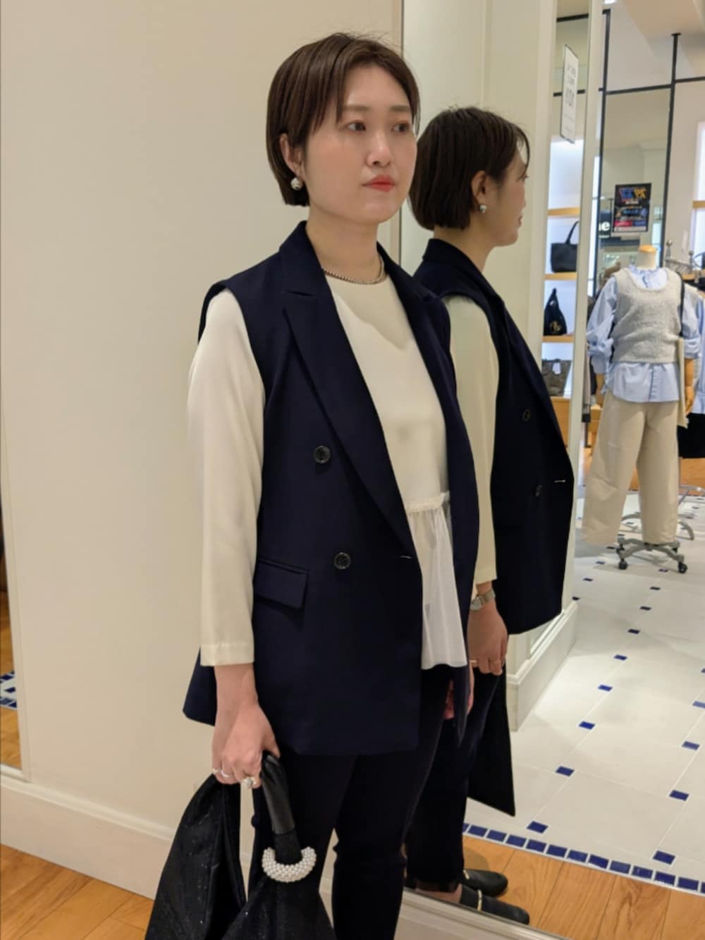 ホワイト系のシャツ/ブラウス、ブルー系のベスト、ブラック系のショルダーバッグを着用したレディースの冬コーディネートの3枚目の写真