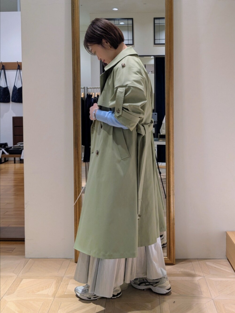 シルバー系のスカート、ブルー系のカーディガン/ボレロ、グリーン系のトレンチコートを着用したレディースの冬コーディネートの4枚目の写真