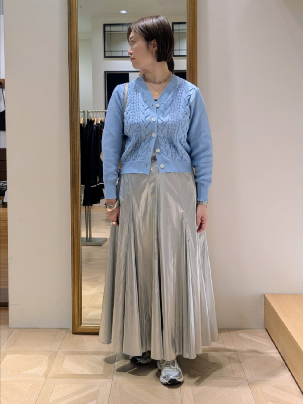 シルバー系のスカート、ブルー系のカーディガン/ボレロ、グリーン系のトレンチコートを着用したレディースの冬コーディネートの9枚目の写真
