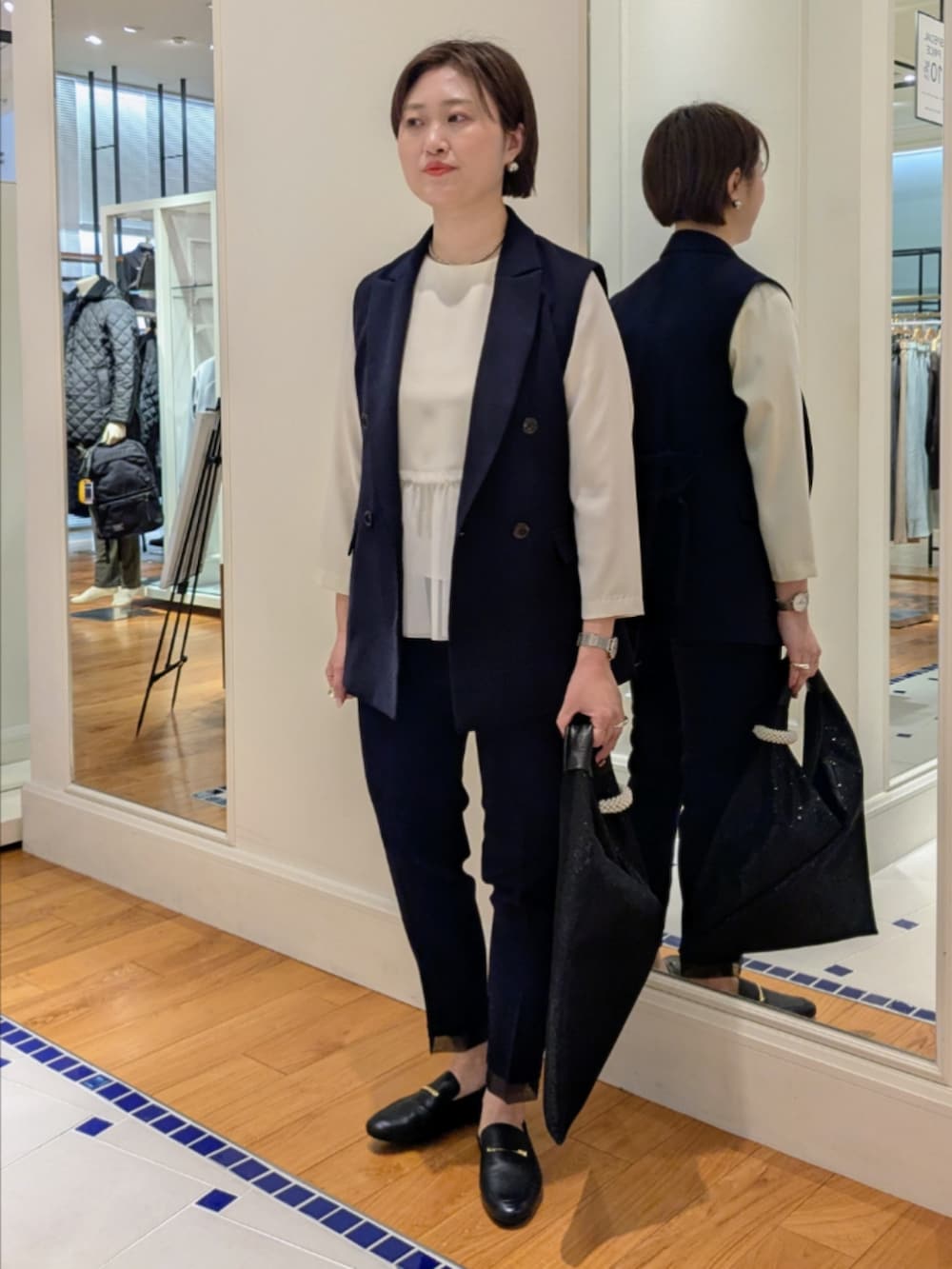 ホワイト系のシャツ/ブラウス、ブルー系のベスト、ブラック系のショルダーバッグを着用したレディースの冬コーディネートの5枚目の写真