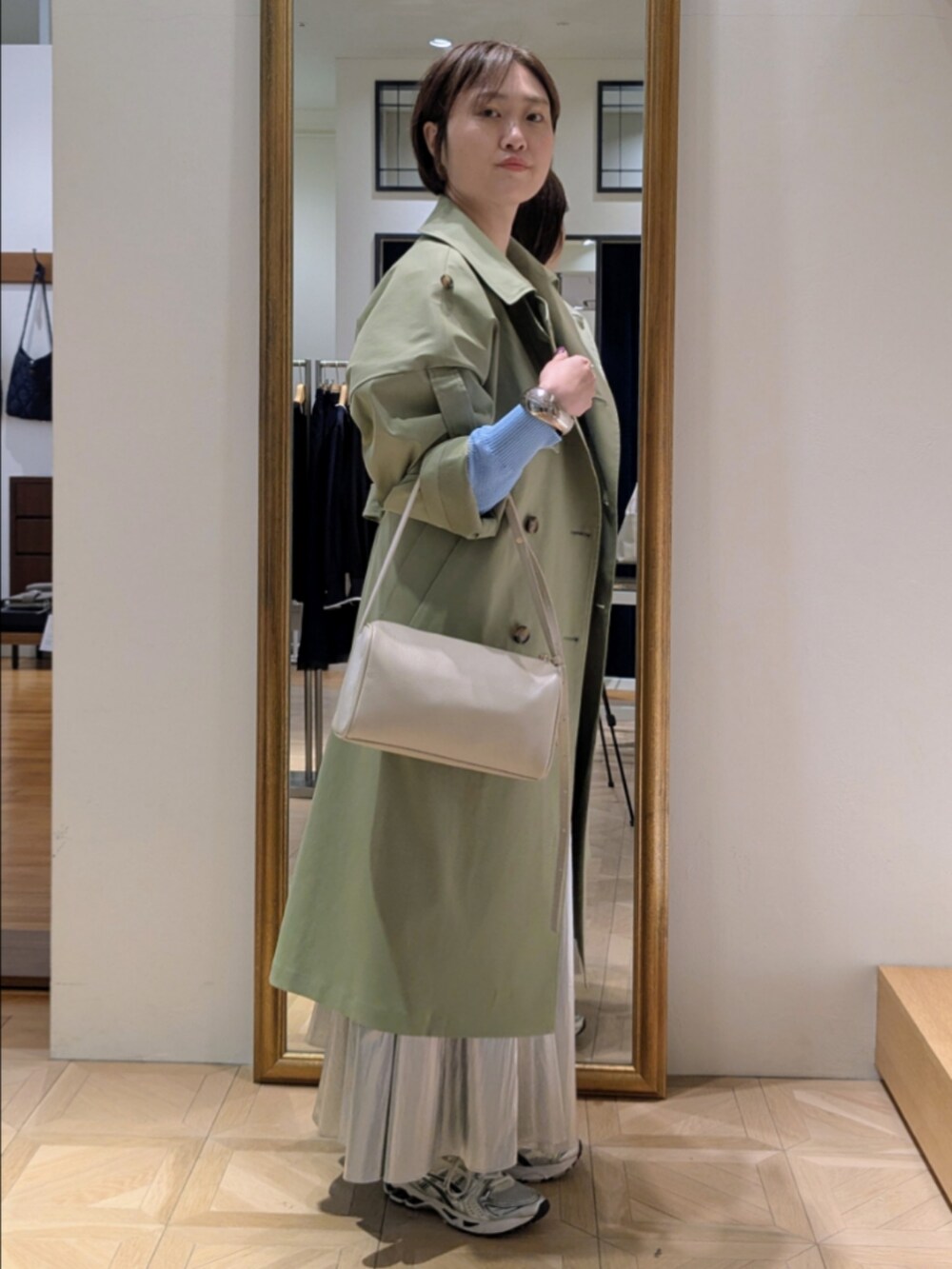 シルバー系のスカート、ブルー系のカーディガン/ボレロ、グリーン系のトレンチコートを着用したレディースの冬コーディネートの3枚目の写真