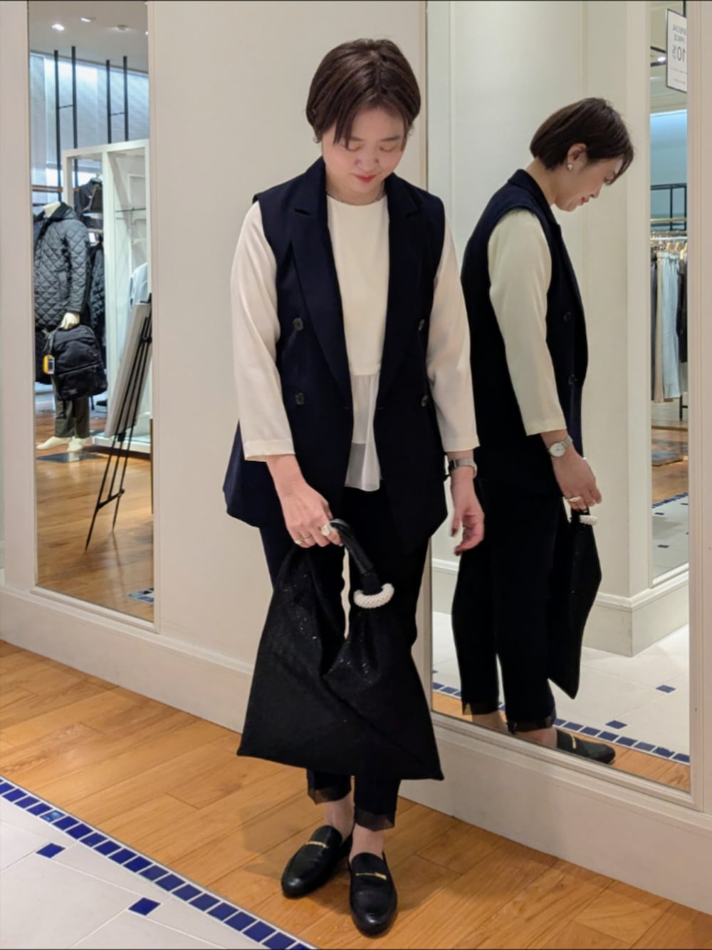 ホワイト系のシャツ/ブラウス、ブルー系のベスト、ブラック系のショルダーバッグを着用したレディースの冬コーディネートの8枚目の写真