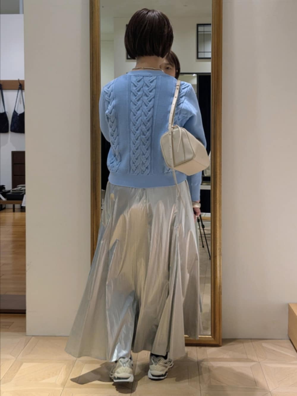 シルバー系のスカート、ブルー系のカーディガン/ボレロ、グリーン系のトレンチコートを着用したレディースの冬コーディネートの10枚目の写真