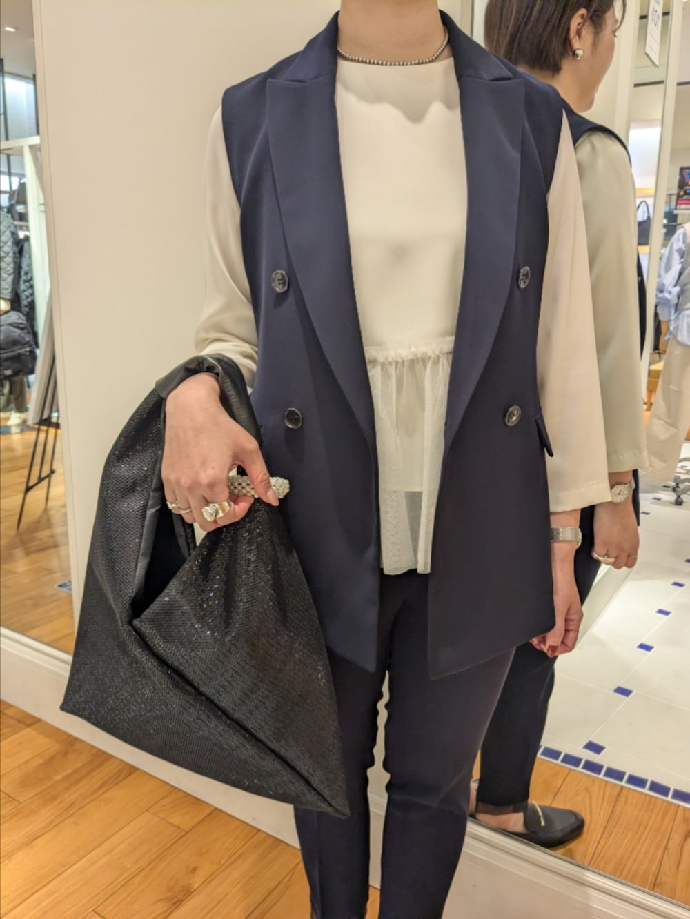 ホワイト系のシャツ/ブラウス、ブルー系のベスト、ブラック系のショルダーバッグを着用したレディースの冬コーディネートの4枚目の写真