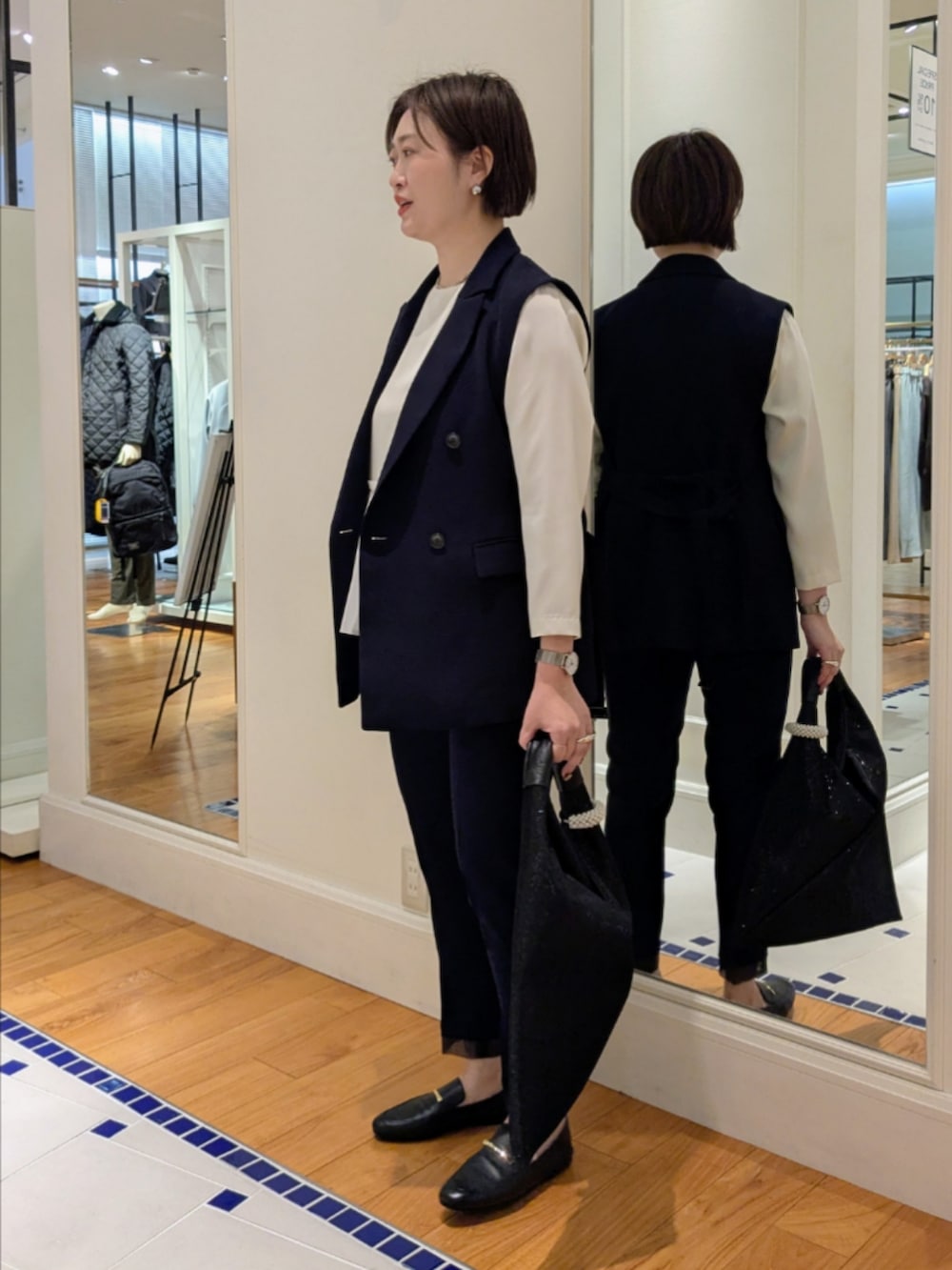 ホワイト系のシャツ/ブラウス、ブルー系のベスト、ブラック系のショルダーバッグを着用したレディースの冬コーディネートの6枚目の写真