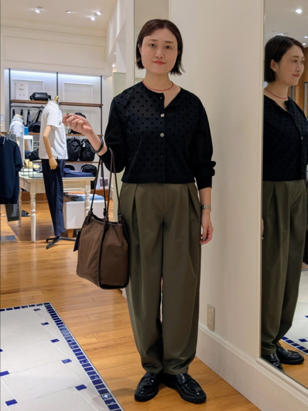 ブラック系のカーディガン/ボレロ、グリーン系のチノパンツ、ブラック系のドレスシューズを着用したレディースの夏コーディネートの4枚目の写真