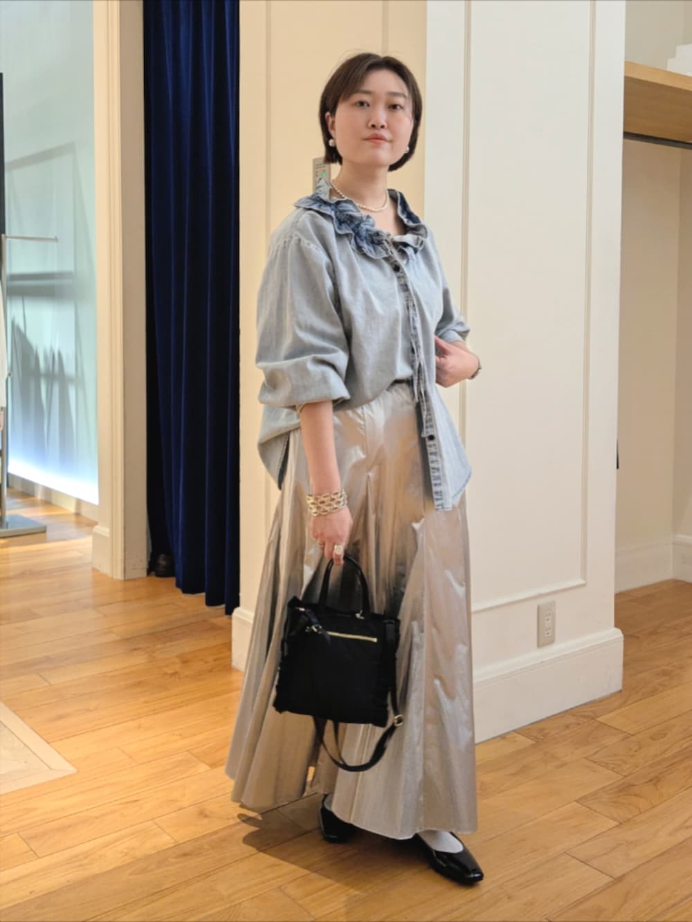 シルバー系のスカート、ブルー系のシャツ/ブラウス、ブラック系のショルダーバッグを着用したレディースの冬コーディネートの6枚目の写真