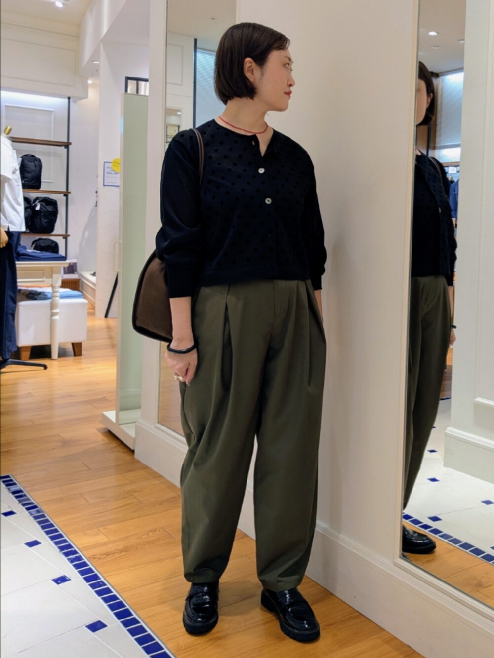ブラック系のカーディガン/ボレロ、グリーン系のチノパンツ、ブラック系のドレスシューズを着用したレディースの夏コーディネートの7枚目の写真