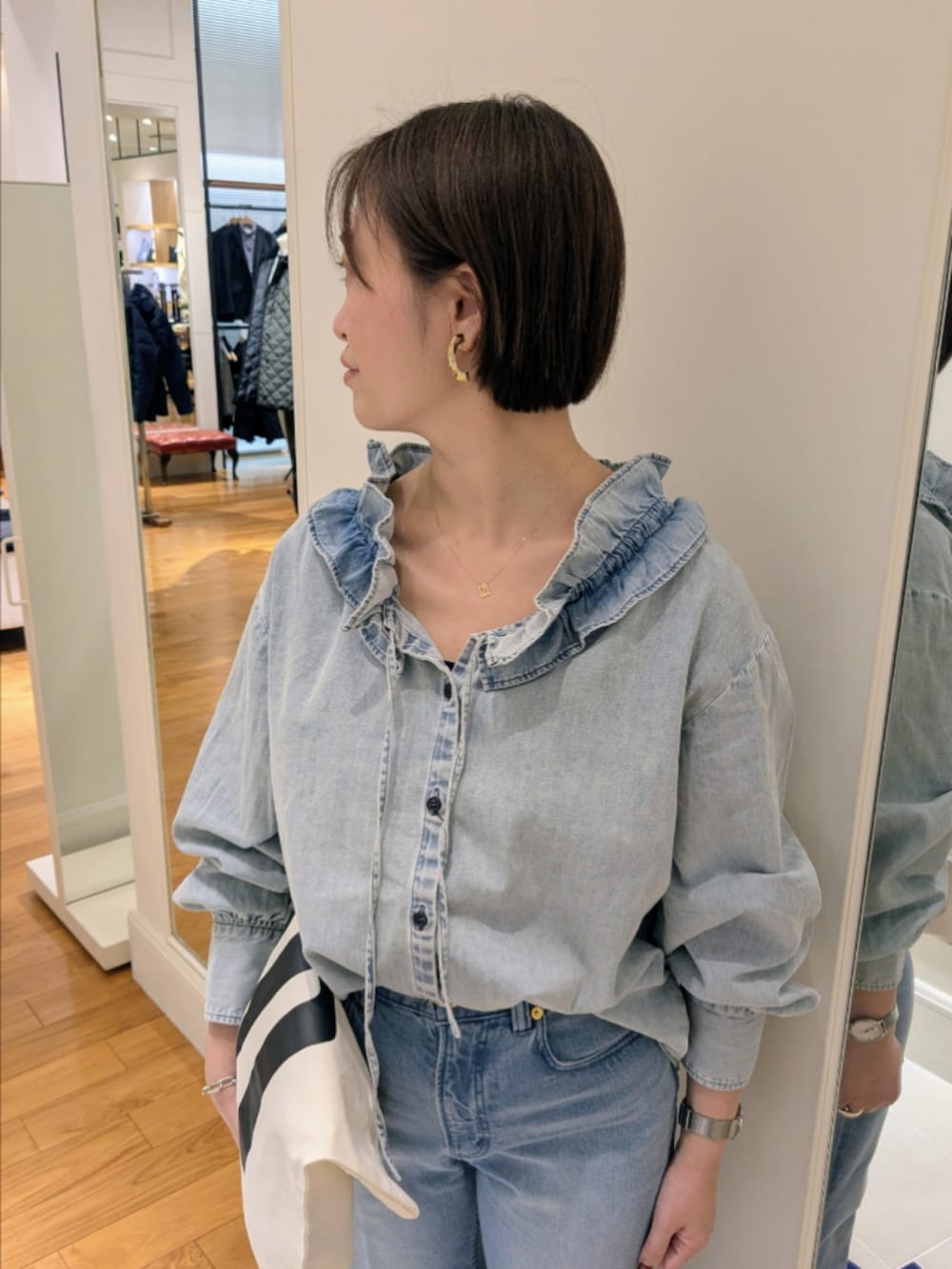 ブルー系のデニムパンツ、ブルー系のシャツ/ブラウス、ホワイト系のトートバッグを着用したレディースの冬コーディネートの3枚目の写真