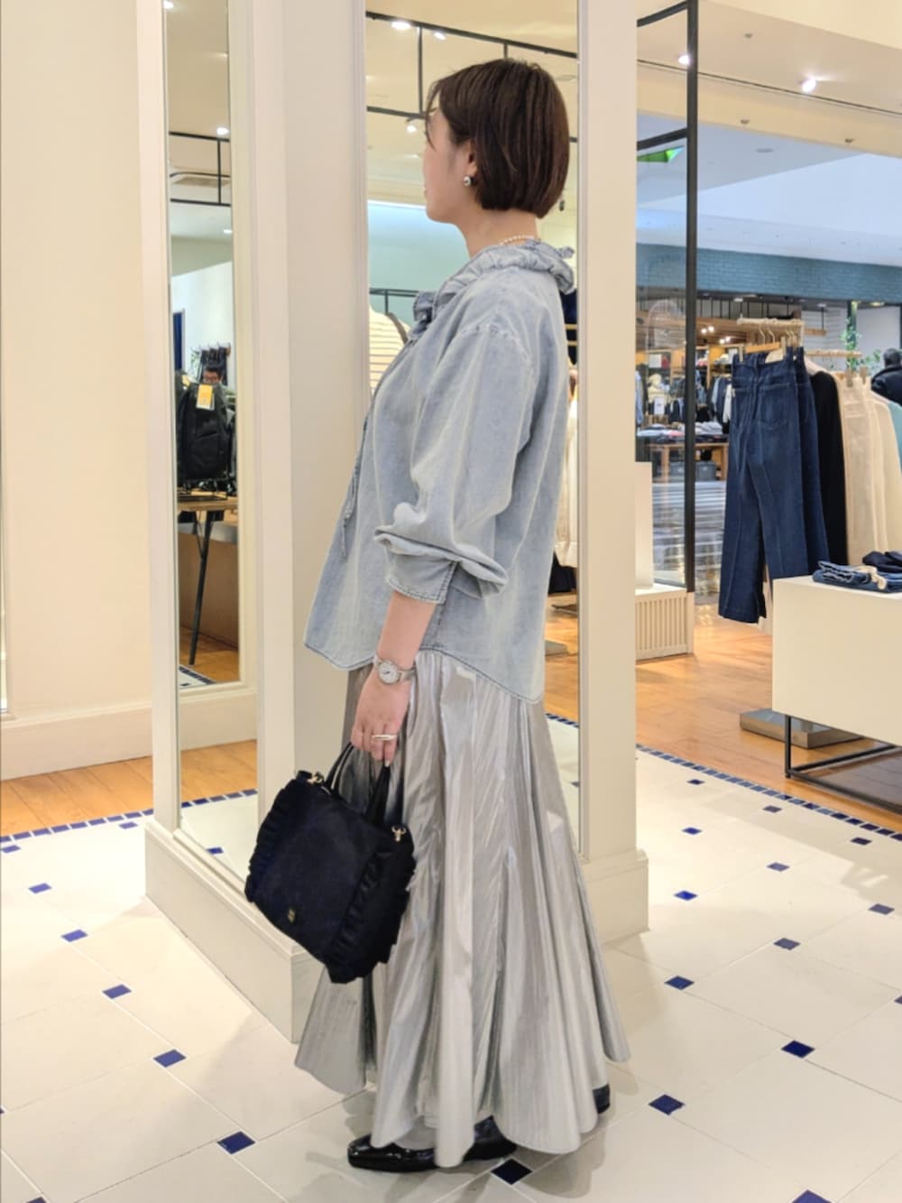 シルバー系のスカート、ブルー系のシャツ/ブラウス、ブラック系のショルダーバッグを着用したレディースの冬コーディネートの5枚目の写真