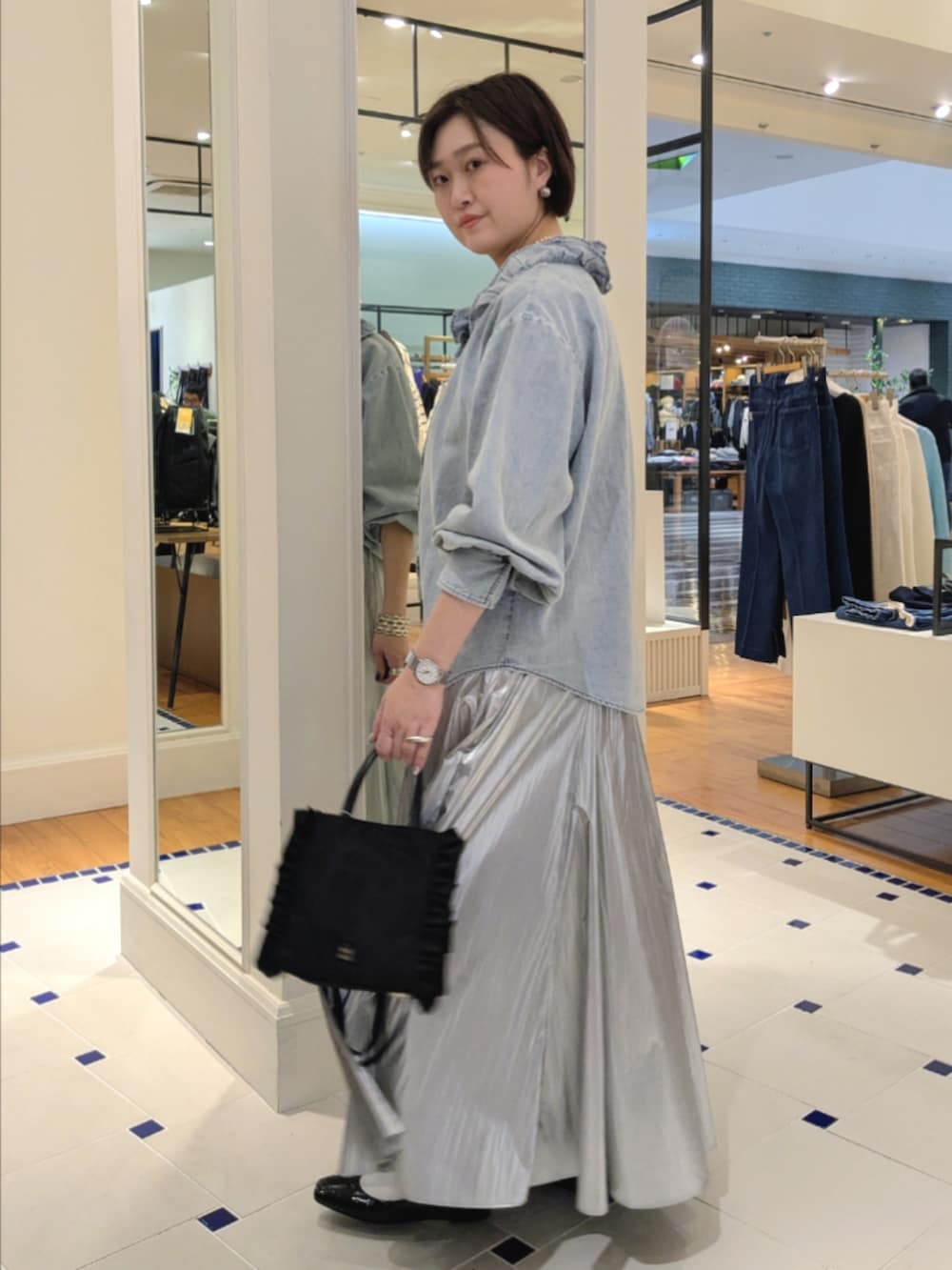 シルバー系のスカート、ブルー系のシャツ/ブラウス、ブラック系のショルダーバッグを着用したレディースの冬コーディネートの4枚目の写真