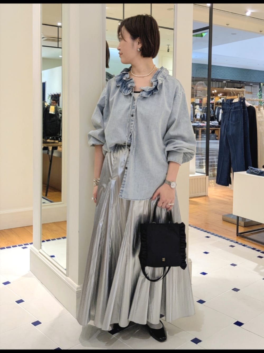 シルバー系のスカート、ブルー系のシャツ/ブラウス、ブラック系のショルダーバッグを着用したレディースの冬コーディネートの2枚目の写真