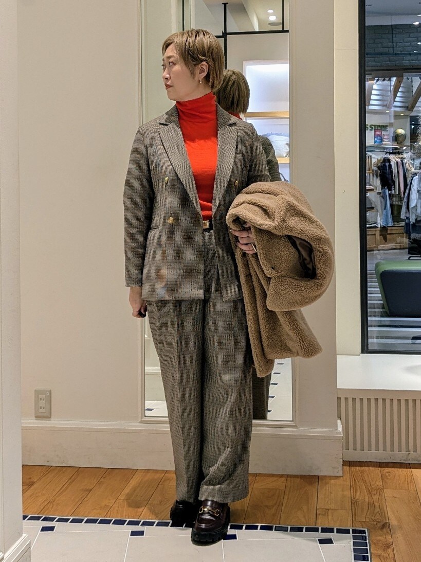 イエロー系のダッフルコート、オレンジ系のニット/セーター、ブラウン系のその他パンツを着用したレディースの冬コーディネートの2枚目の写真