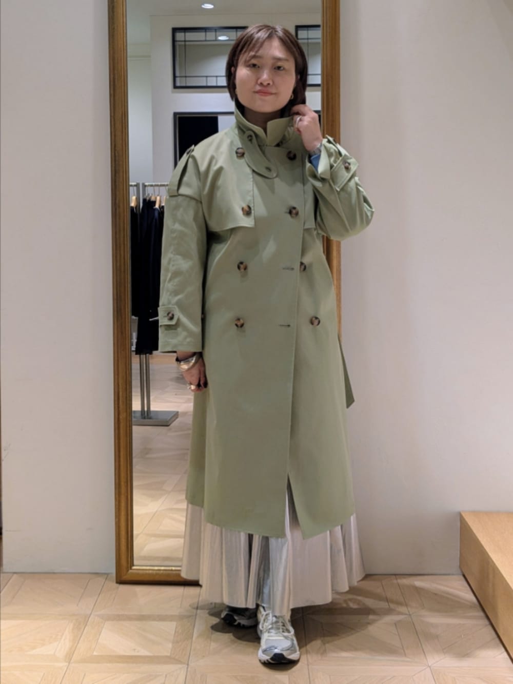 シルバー系のスカート、ブルー系のカーディガン/ボレロ、グリーン系のトレンチコートを着用したレディースの冬コーディネートの6枚目の写真