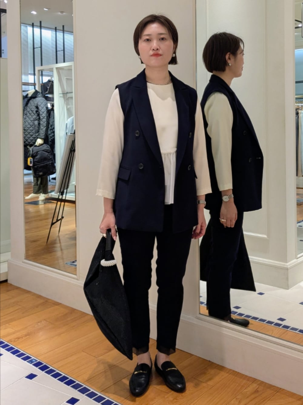 ホワイト系のシャツ/ブラウス、ブルー系のベスト、ブラック系のショルダーバッグを着用したレディースの冬コーディネートの9枚目の写真