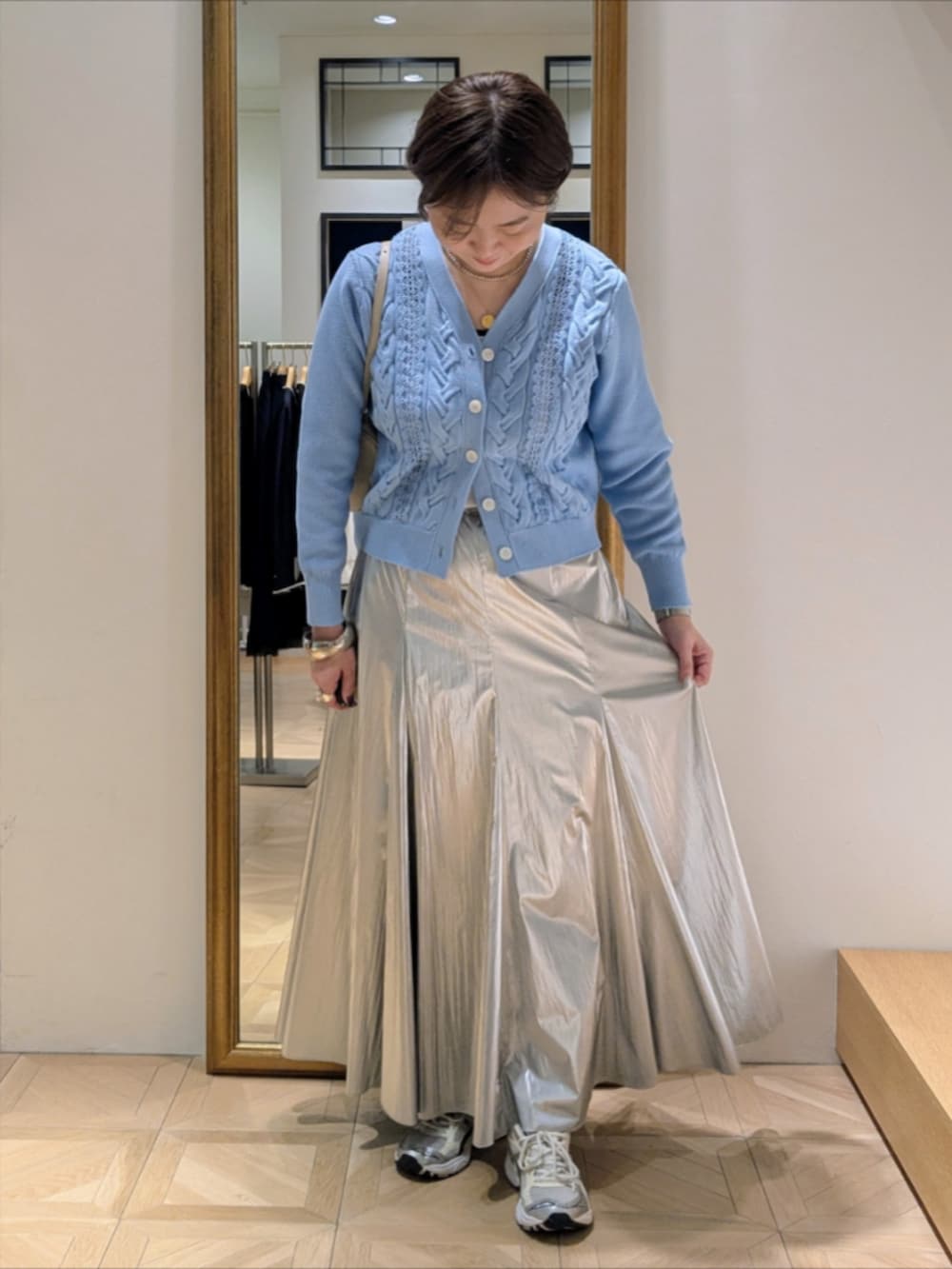 シルバー系のスカート、ブルー系のカーディガン/ボレロ、グリーン系のトレンチコートを着用したレディースの冬コーディネートの8枚目の写真