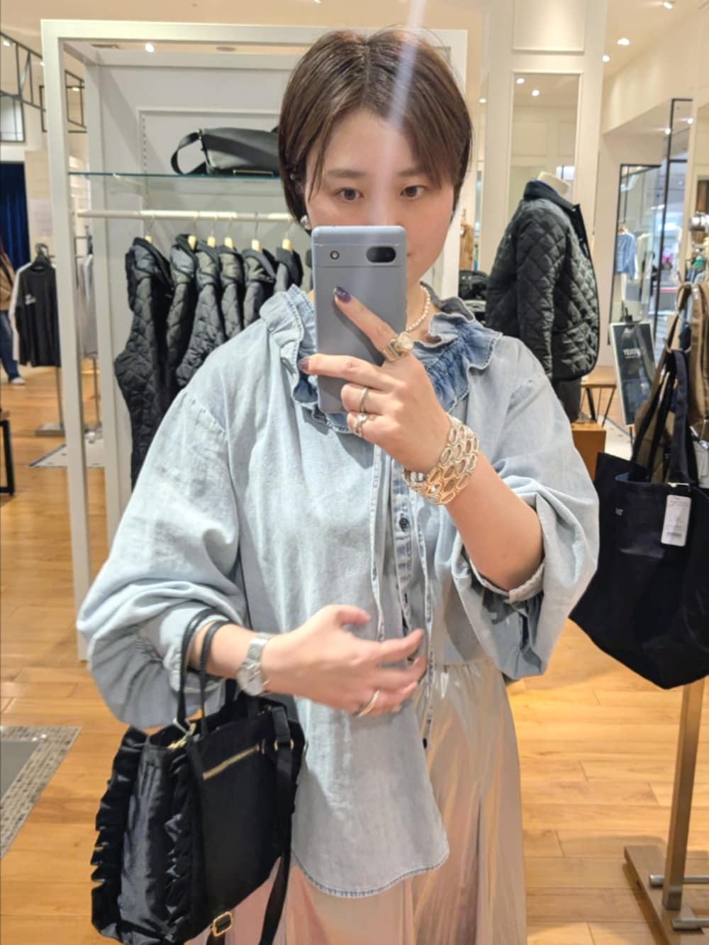 シルバー系のスカート、ブルー系のシャツ/ブラウス、ブラック系のショルダーバッグを着用したレディースの冬コーディネートの9枚目の写真