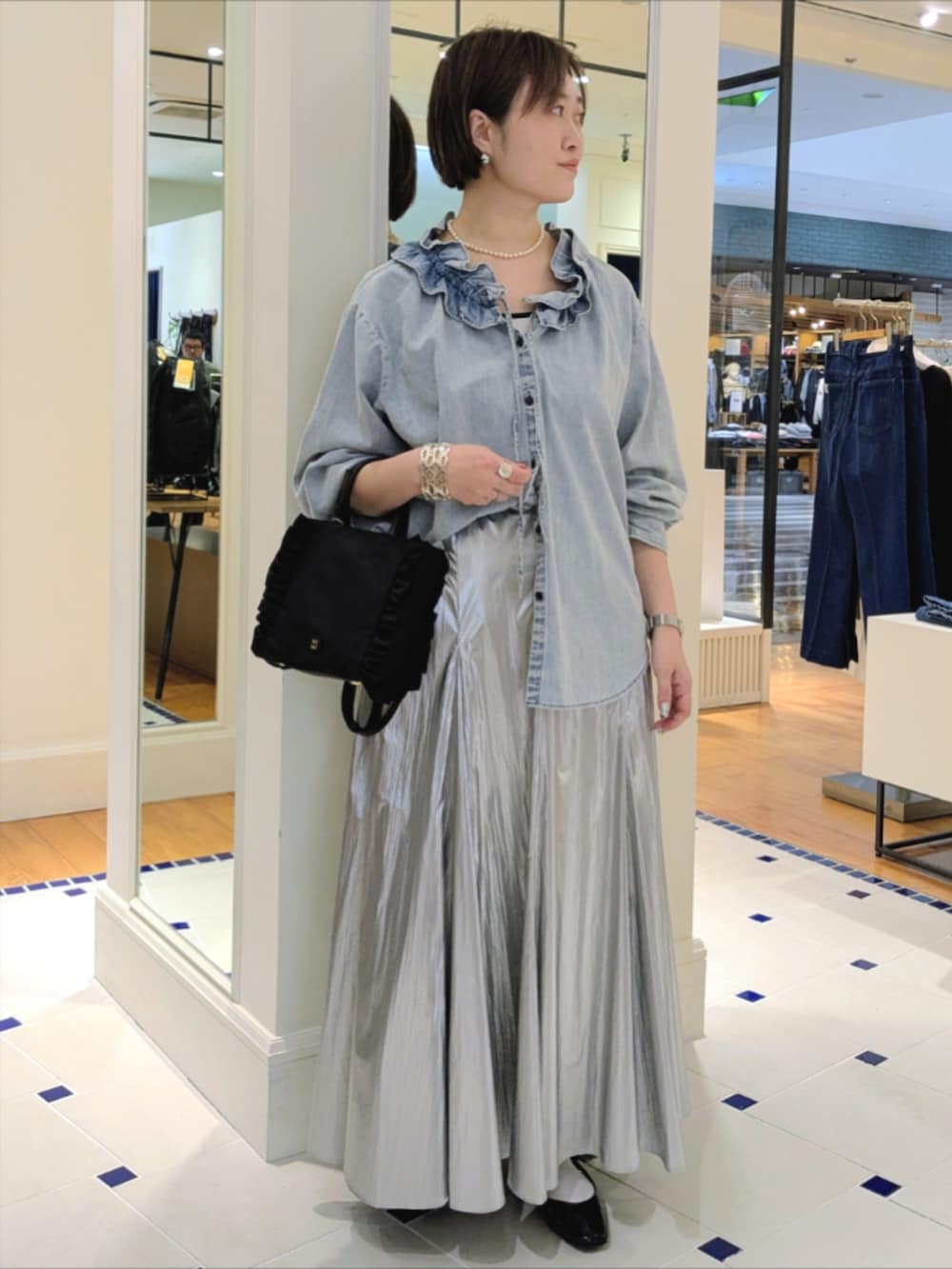 シルバー系のスカート、ブルー系のシャツ/ブラウス、ブラック系のショルダーバッグを着用したレディースの冬コーディネートの3枚目の写真