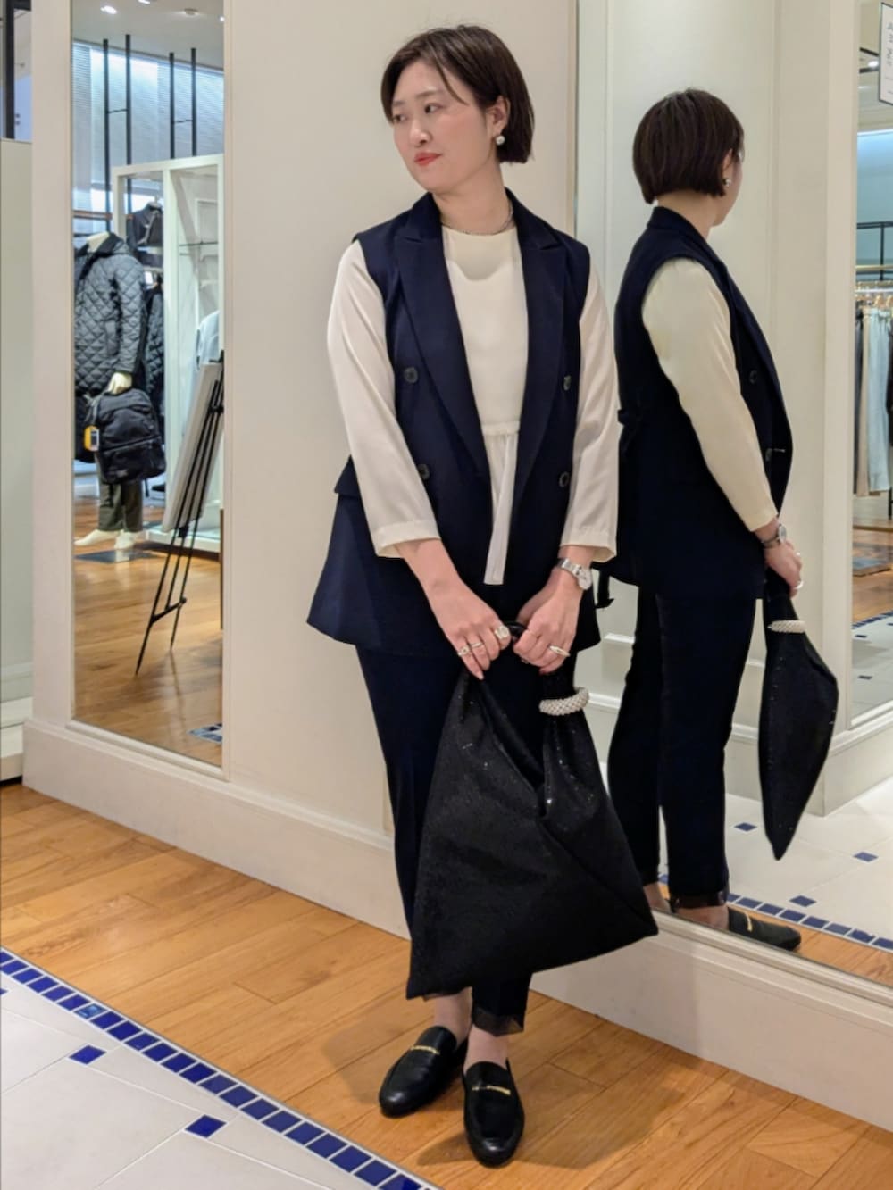 ホワイト系のシャツ/ブラウス、ブルー系のベスト、ブラック系のショルダーバッグを着用したレディースの冬コーディネートの2枚目の写真