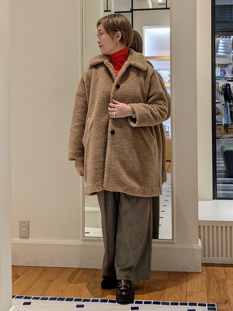 イエロー系のダッフルコート、オレンジ系のニット/セーター、ブラウン系のその他パンツを着用したレディースの冬コーディネートの3枚目の写真